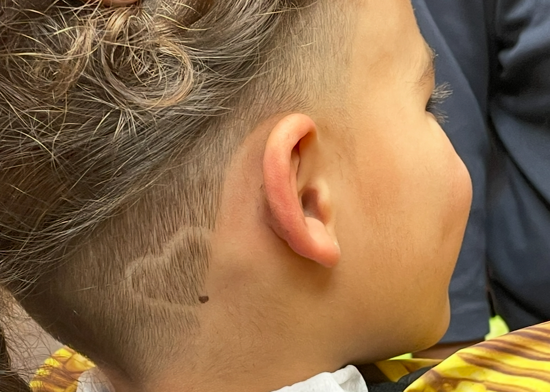 Detail van een kinderkapsel met een ingeschoren haarontwerp